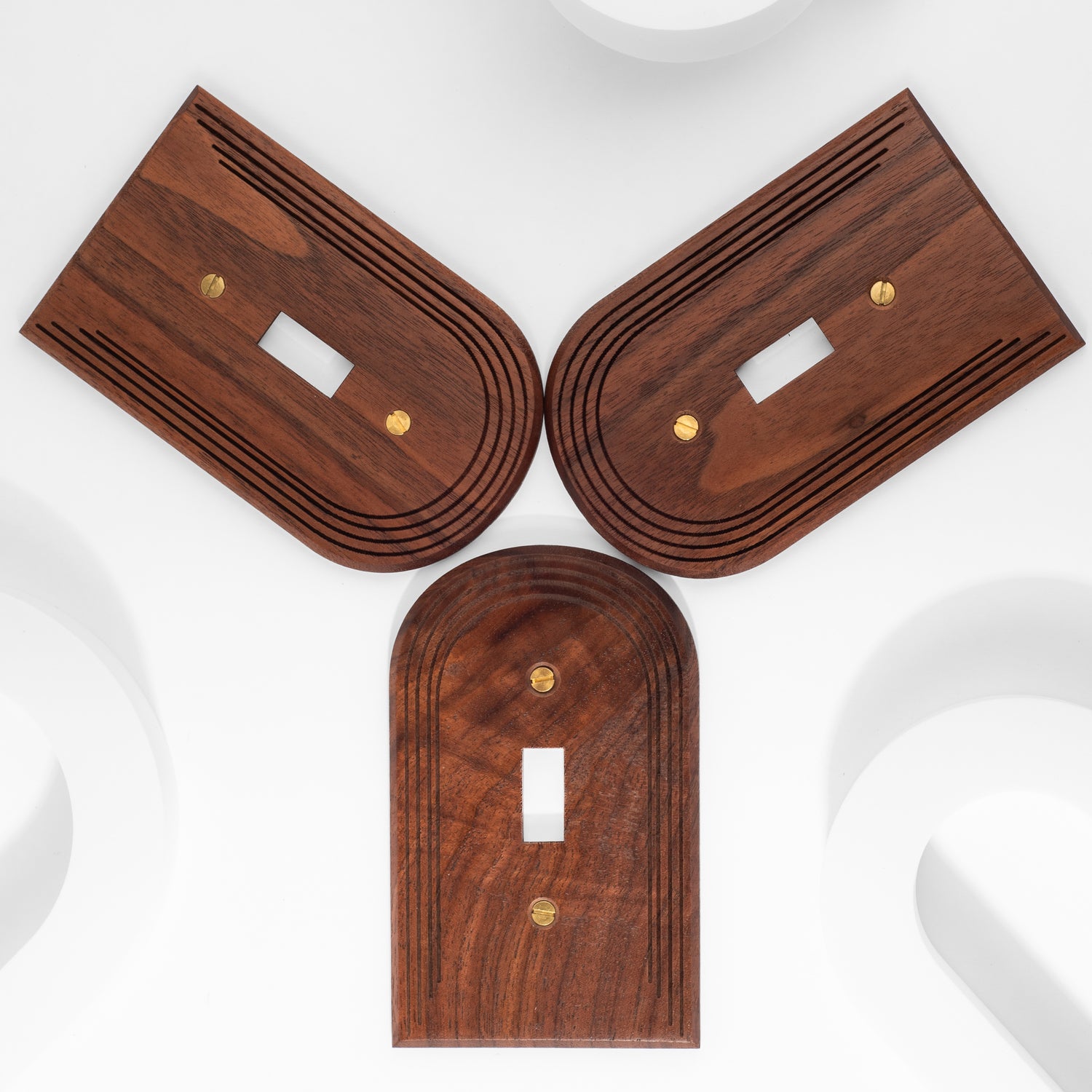 3 single toggle walnut light switch plates on a white background in a Y shape. The light switch plates have a flat bottom and an arched top. The surface engraving is 3 offset lines that follow the arch 